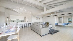 A spacious living area with a modern kitchen, a dining table set for four, and a large sofa.