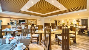 A spacious dining area with multiple tables and chairs, a bar in the background, and a modern ceiling design. - Commander Suites de Boracay (Boracay Island)