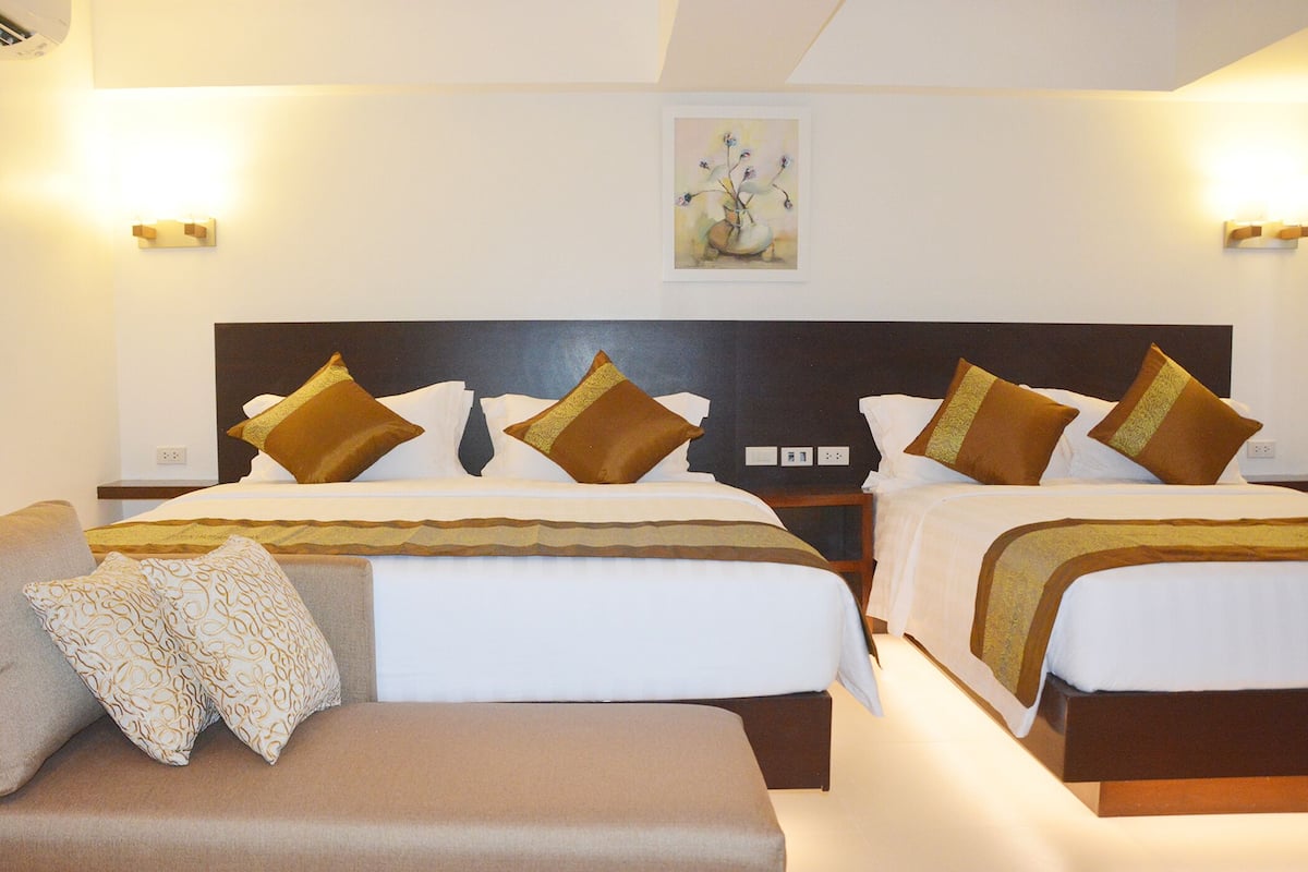 A hotel room with two beds, a sofa, and a nightstand.