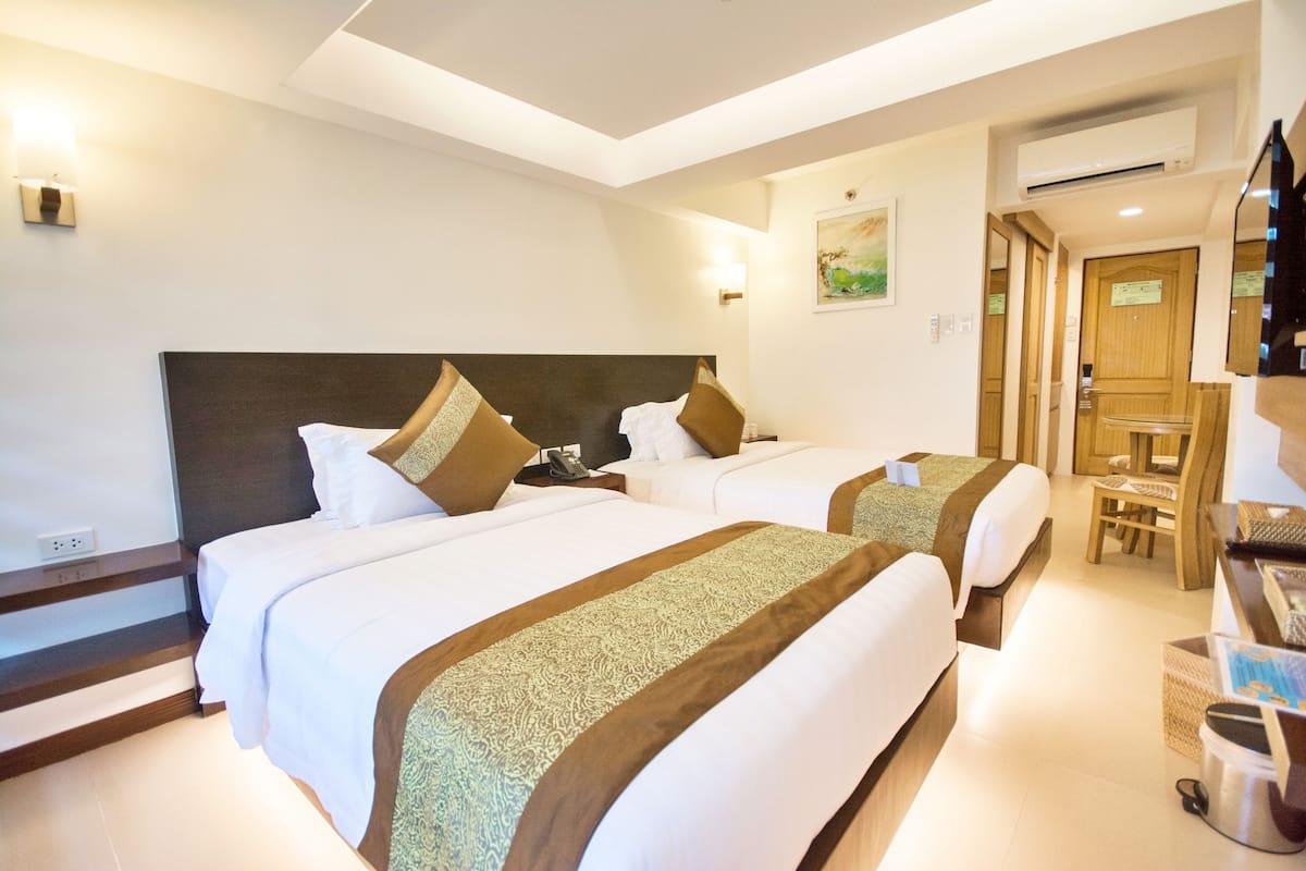 A hotel room with two beds, a desk, and a chair.