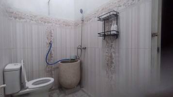 A small bathroom with a toilet, a shower, and a wall-mounted shelf.