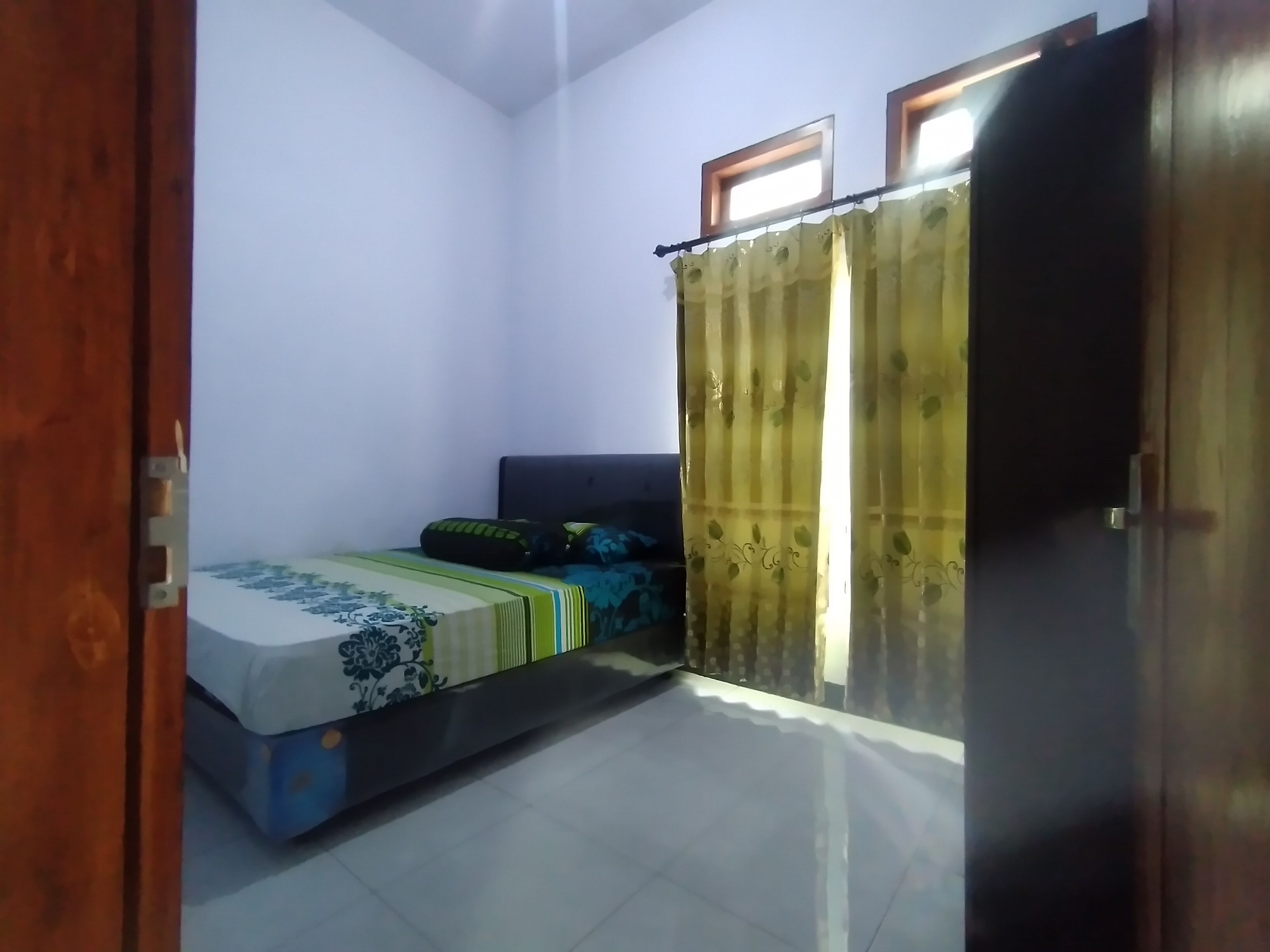 Un dormitorio con cama, armario y ventana con cortinas.