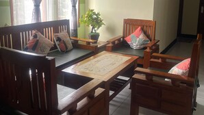 Una sala de estar tradicional con muebles de madera, una mesa de centro y una planta en maceta.