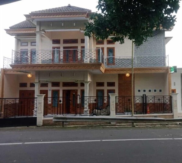 A two-story building with a balcony, a gated entrance, and a street view.