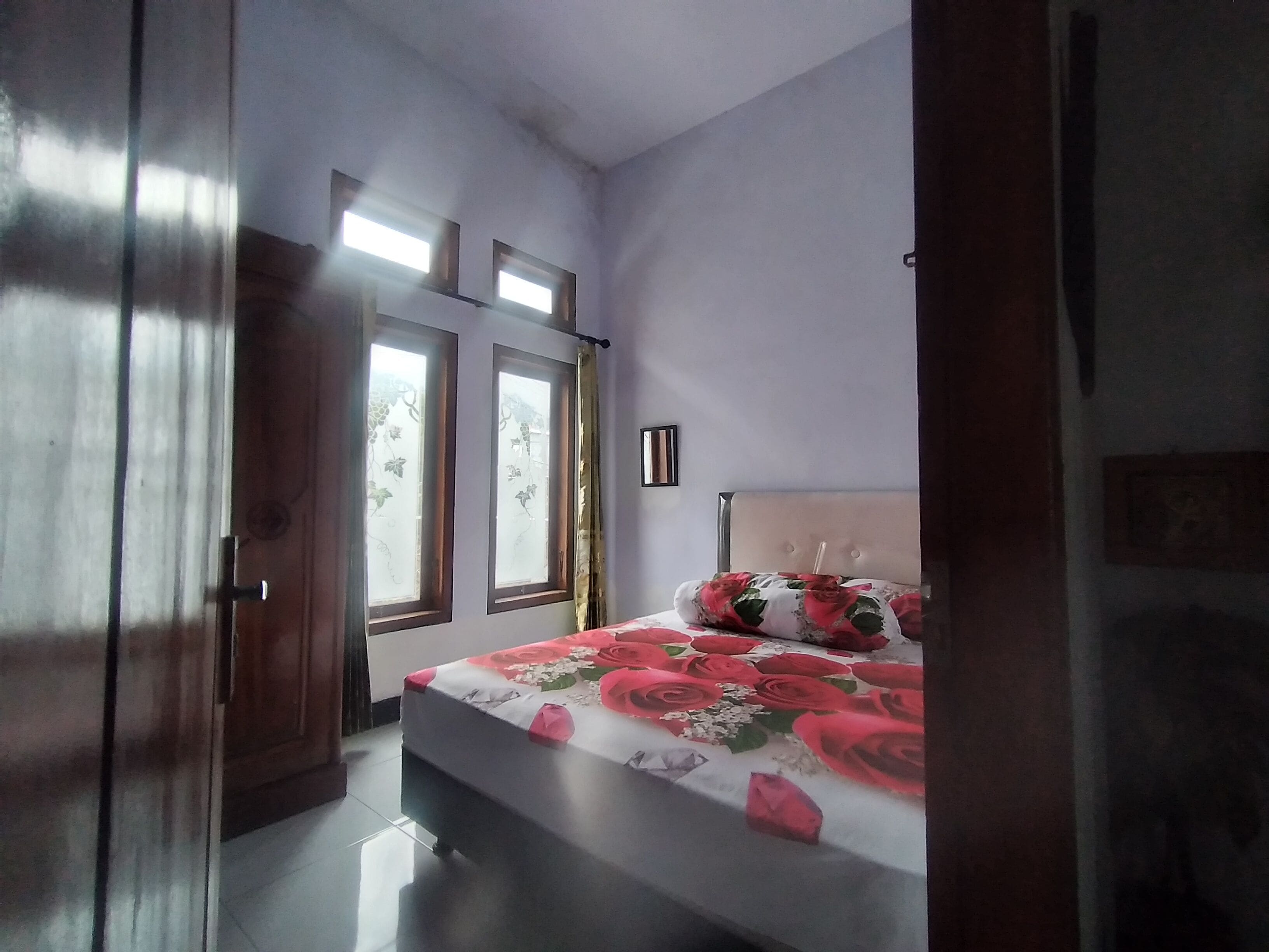 A bedroom with a bed, a window with curtains, and a door.