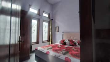 Un dormitorio con cama, ventana con cortinas y una puerta.