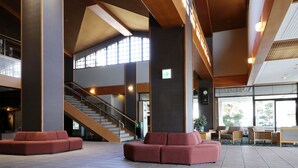 A spacious lobby with a staircase, seating areas, and large windows. - Isawa Tokiwa Hotel (Fuefuki)