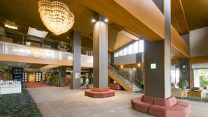 A spacious lobby with high ceilings, a large chandelier, and a staircase leading to an upper level. - Isawa Tokiwa Hotel (Fuefuki)