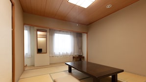 A traditional Japanese room with tatami flooring, a low table, and a sliding door. - Tabist Yabuki Station Hotel (Yabuki)