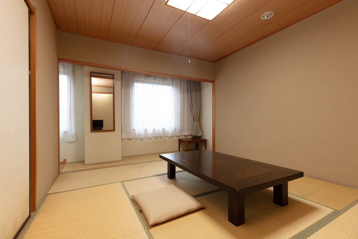 A traditional Japanese room with tatami flooring, a low table, and a sliding door.