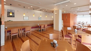 A modern restaurant with wooden flooring, multiple seating areas, pendant lighting, and a clean, minimalist design. - Tabist Yabuki Station Hotel (Yabuki)