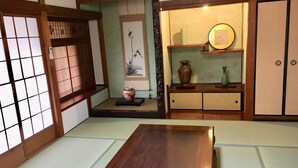 A traditional Japanese room with tatami flooring, a low wooden table, sliding doors, and a shelf with decorative items. - Rikyuan Sen (Izumisano)