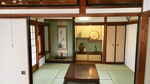 A traditional Japanese room with tatami flooring, a low wooden table, sliding doors, and a shelf with decorative items. - Rikyuan Sen (Izumisano)
