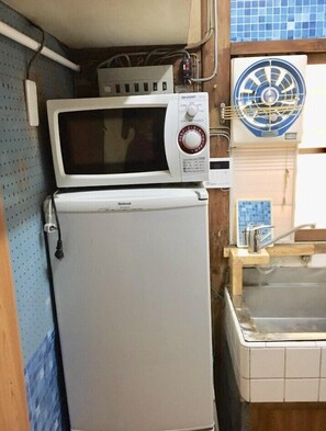A compact kitchen with a microwave and a small refrigerator. - Rikyuan Sen (Izumisano)