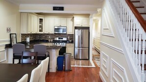 A modern kitchen with white cabinetry, stainless steel appliances, and a dining area with a wooden table and chairs.