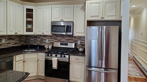 A modern kitchen with white cabinetry, a stainless steel refrigerator, a microwave, and a stove.
