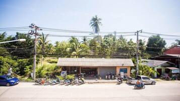 A small building with a tiled roof, surrounded by parked motorcycles and a few cars.