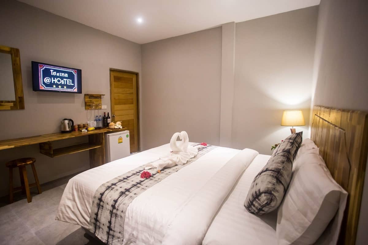 A hotel room with a bed, a desk, a television, and a wall-mounted sign.
