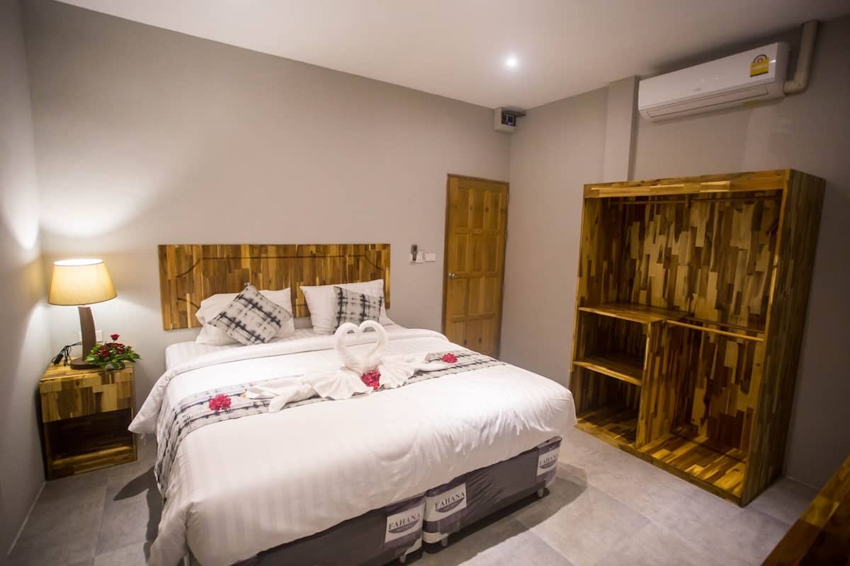 A neatly made bed with a wooden headboard, a bedside table with a lamp, and a wardrobe with a wooden design.