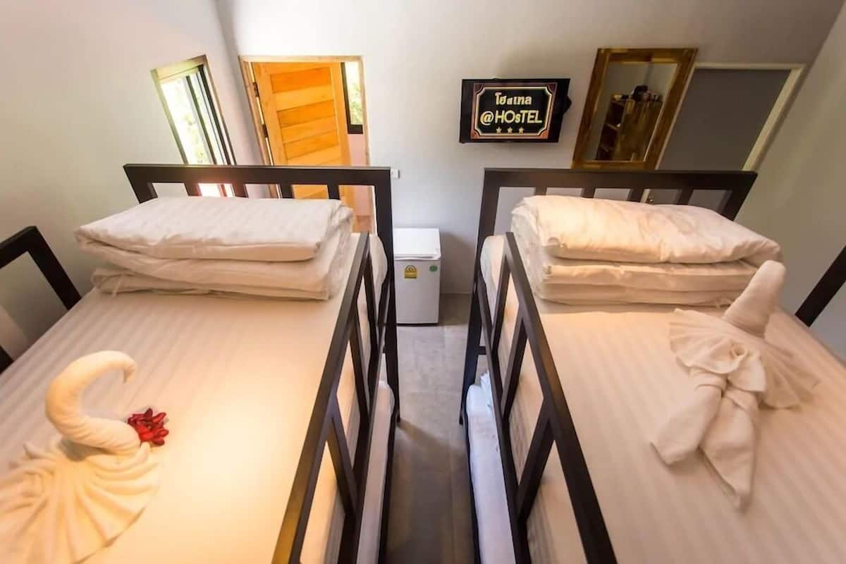 A hotel room with two single beds, a small bedside table, a wall-mounted sign, and a mirror.