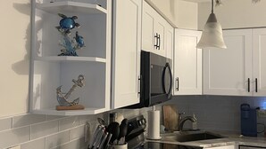 Una cocina moderna con armarios blancos, un microondas negro y una lámpara colgante.