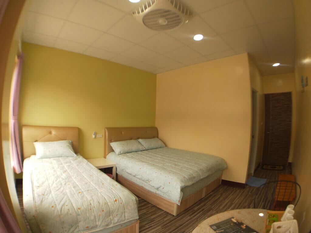 Una habitación con dos camas, un ventilador de techo y una puerta que da a otra zona.