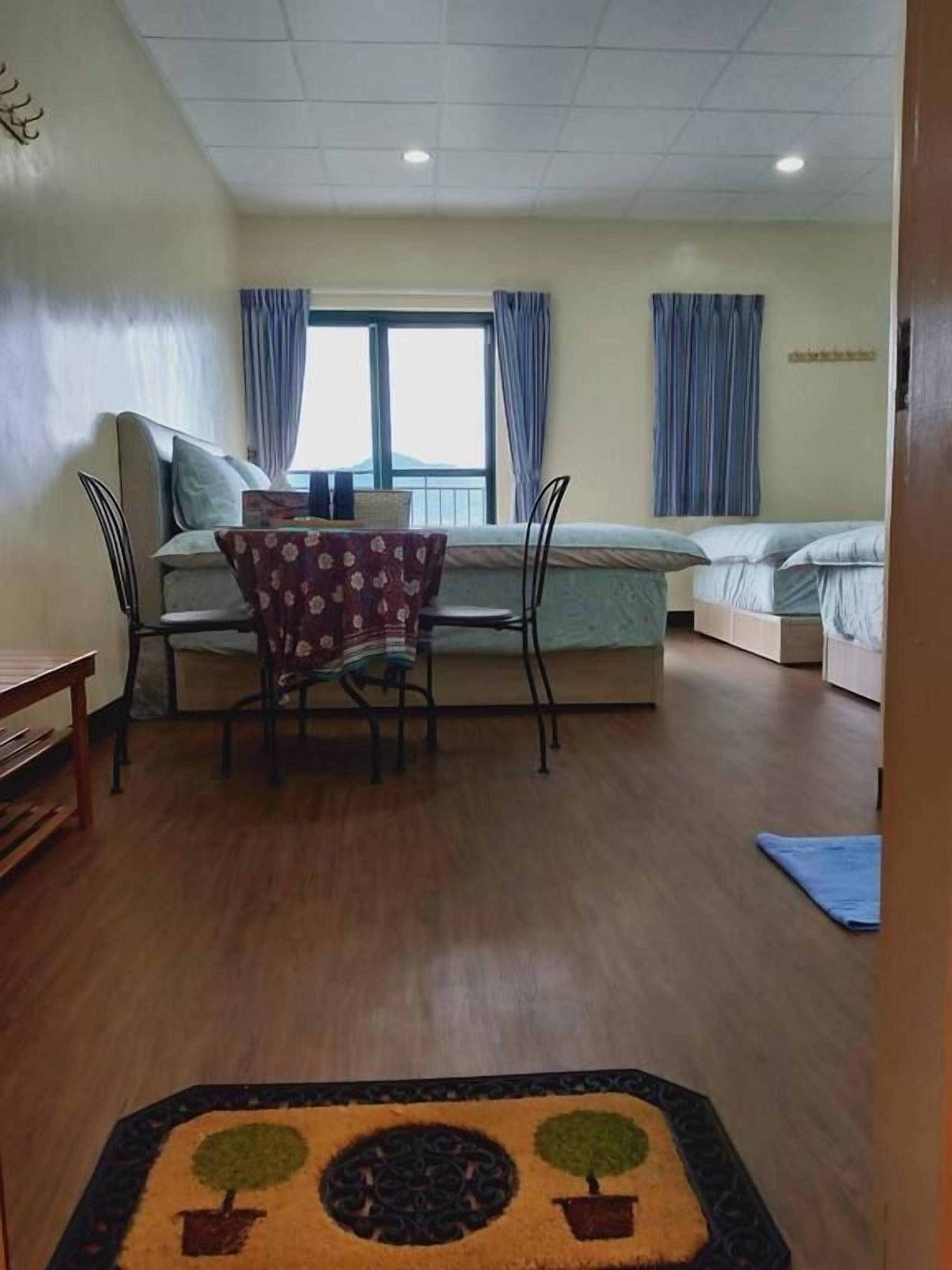 A room with a bed, a desk, and a chair. There are curtains on the windows.