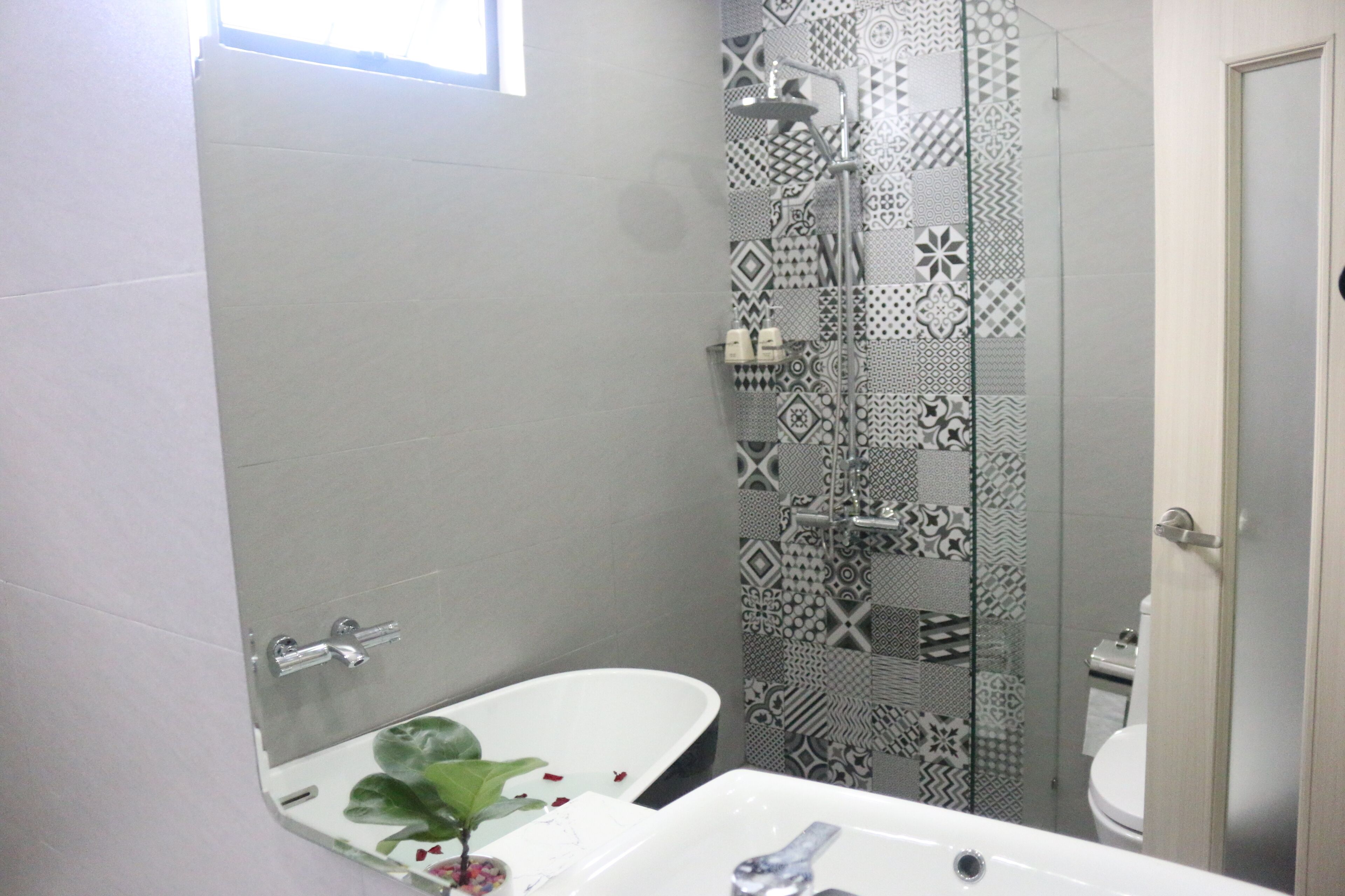 Une salle de bain avec une baignoire blanche, une douche aux carreaux décorés et des toilettes.