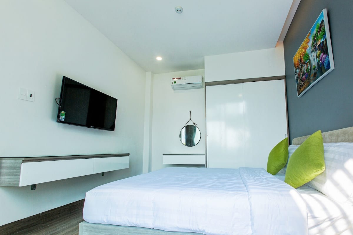 Une chambre d’hôtel moderne équipée d’un lit, d’un téléviseur fixé au mur, d’un miroir et d’un tableau.