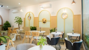 Un intérieur moderne avec des tables et des chaises rondes, un grand miroir et des plantes en pot.