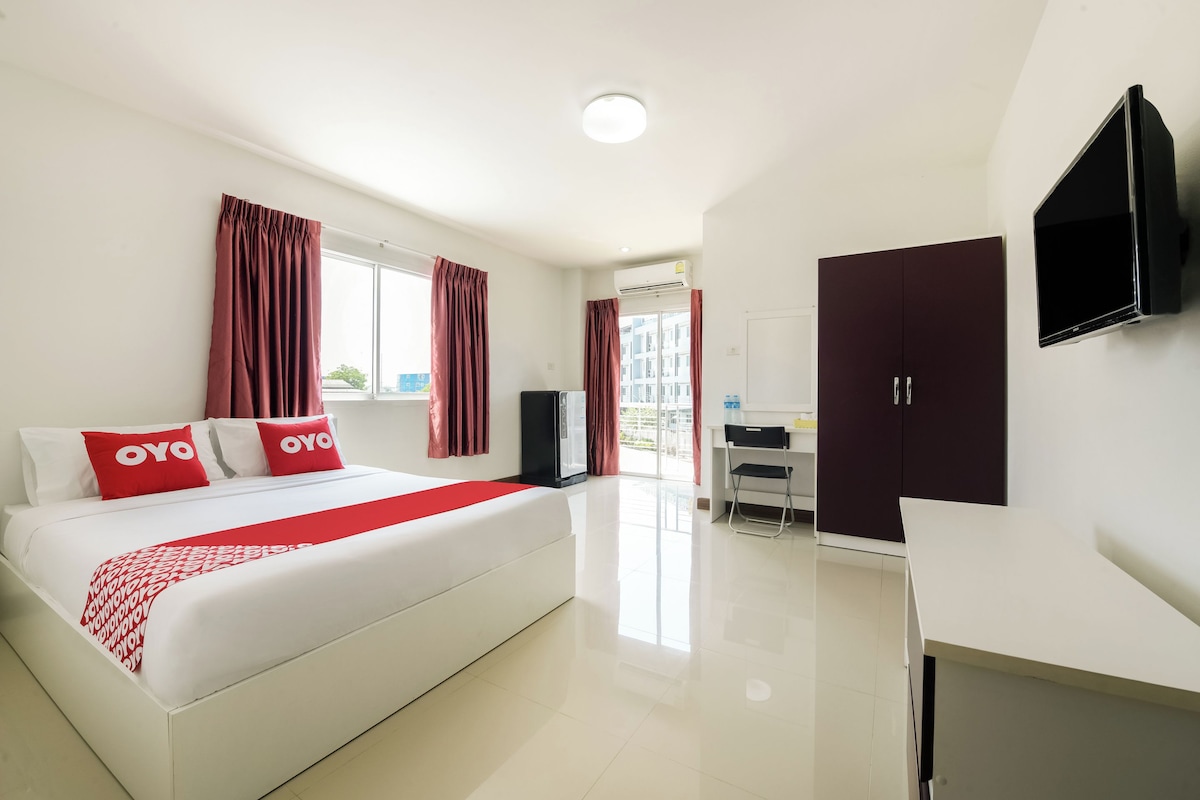 A hotel room with a bed, a desk, a wardrobe, and a TV.