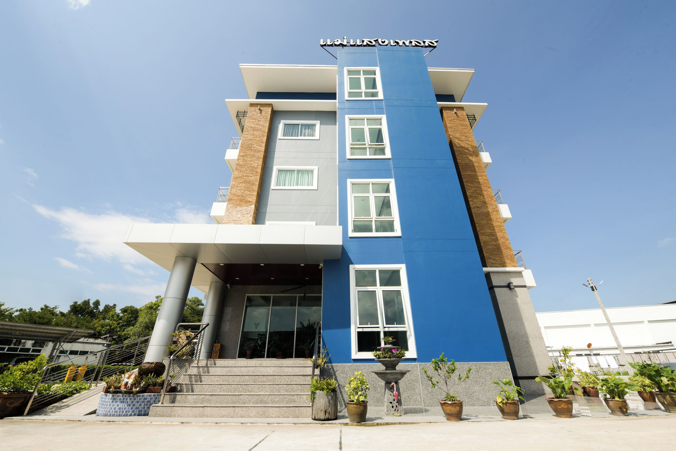 A modern hotel with a blue and grey facade, multiple windows, and a staircase leading to the entrance.