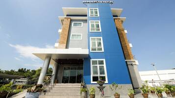 A modern hotel with a blue and grey facade, multiple windows, and a staircase leading to the entrance.