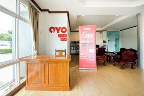 A reception area with a wooden desk, a large OYO sign, and a promotional stand offering a 100% discount voucher. - OYO 350 Mae Saeng Place (Si Racha)