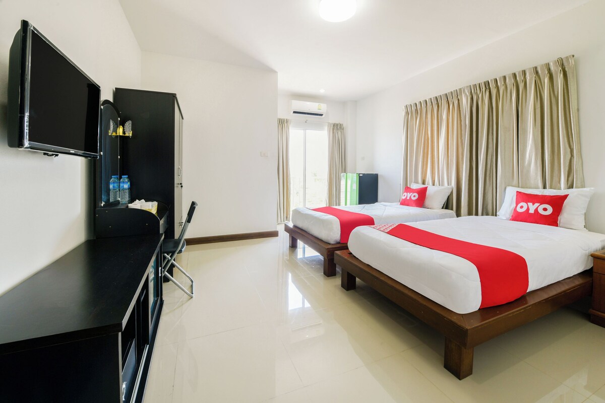 A hotel room with two beds, a TV, a desk, and a wardrobe.