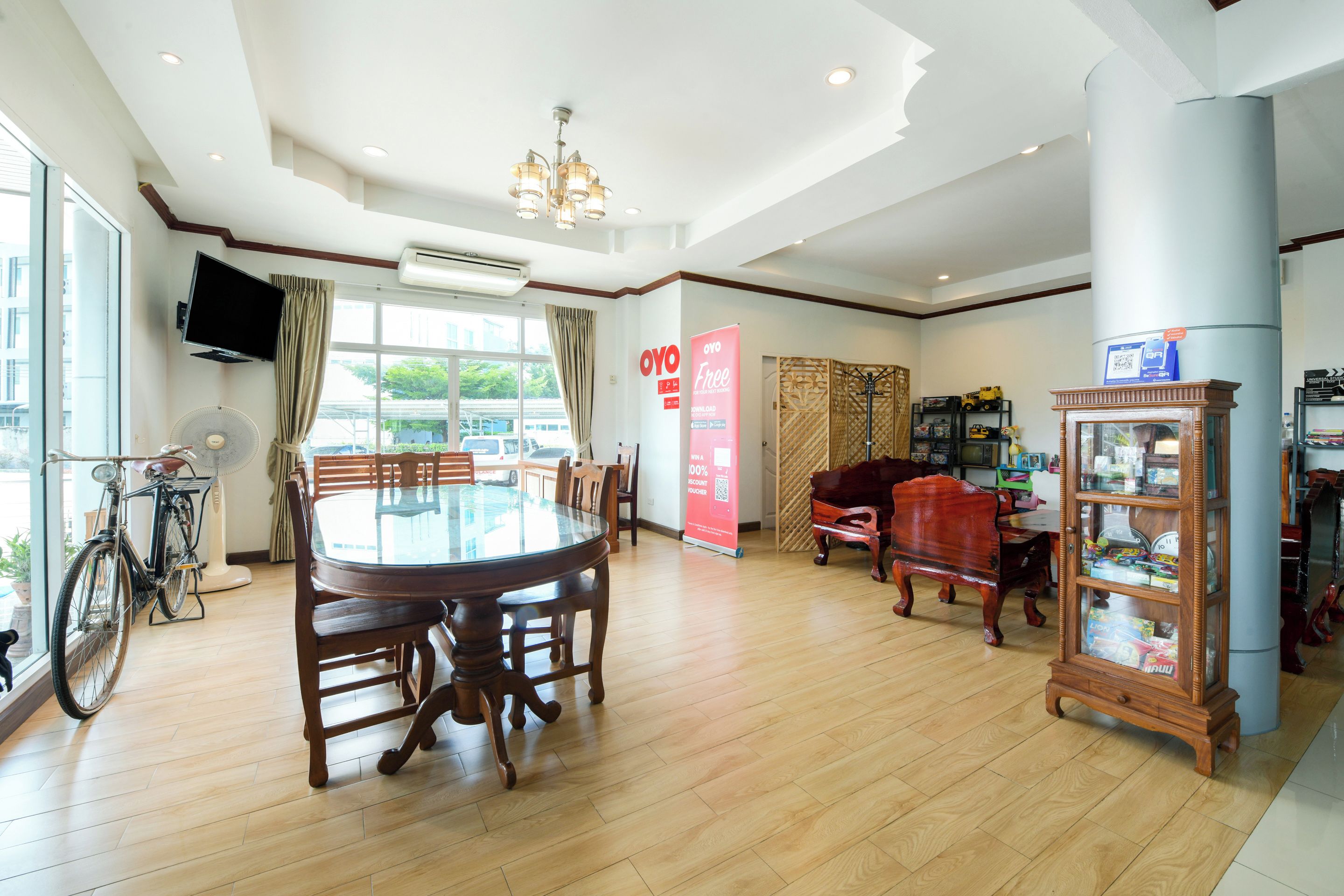 A spacious room with a round wooden dining table, chairs, a piano, and a cabinet with glass doors.
