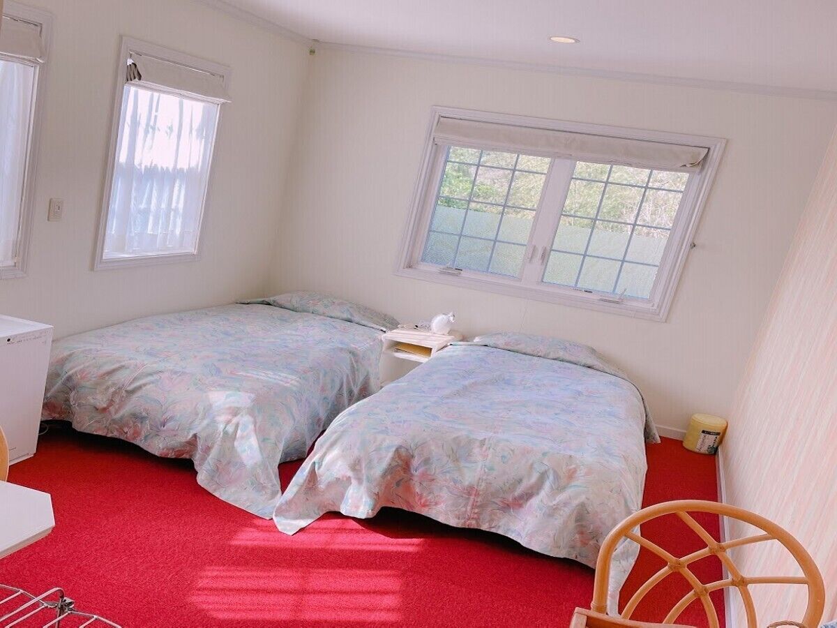 Ein Schlafzimmer mit zwei Betten, einem Schreibtisch, einem Stuhl und einem Fenster.