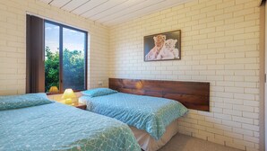 A bedroom with two beds, a window, a painting, and a lamp. - Apollo Unit 27 - Ground Floor (Narooma)