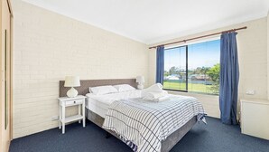 Une chambre d’hôtel avec un lit, deux tables de chevet, une fenêtre avec des rideaux et une vue sur l’extérieur.
