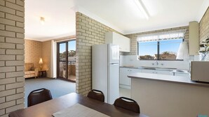 Eine moderne Küche mit Kühlschrank, ein Essbereich mit Tisch und Stühlen sowie ein Blick durch ein Fenster.