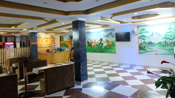 Un vestíbulo de hotel con piso a cuadros, una recepción, un mural grande de caballos y un letrero de Coca-Cola.