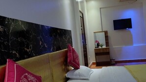 Habitación de hotel con dos camas, cabecera de mármol, televisor montado en la pared y un techo con diseño de estrellas y luna.