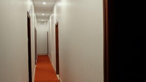 Un pasillo con alfombra roja, paredes blancas y una puerta numerada con el número 607.