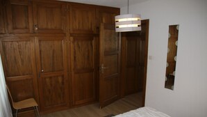 Un dormitorio con armarios de madera, una cama, una silla y un espejo en la pared.