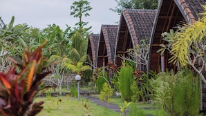 Um edifício de estilo tradicional com telhado em telhas, rodeado por vegetação exuberante e um jardim bem cuidado.