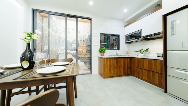 Une cuisine moderne avec des meubles en bois, un four à micro-ondes encastré et une grande fenêtre donnant sur un jardin.