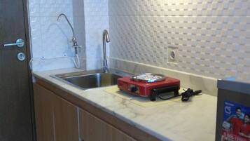 Een koelkast, een kookplaat, kookgerei, borden en bestek