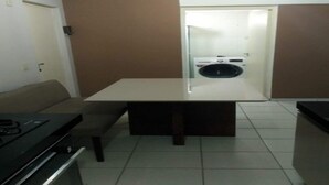 Un espai vital reduït amb petita cuina, taula de dinar i sofà.