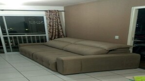 Habitació amb un sofà llit, una porta corredissa de vidre que dona a un balcó, i un terra d'rajola.