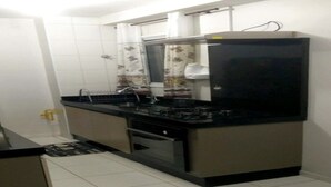 Una cuina compacta amb taulell negre, electrodomèstics d'acer inoxidable i parets revestides de rajoles blanques.